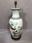 Chinese style ceramic lamp base depicting peacocks, on wooden stand