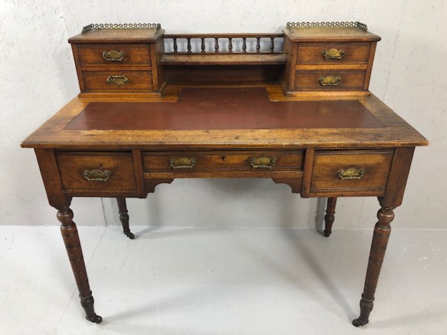 Antique writing desk on turned legs and castors with burgundy leather insert and gallery with