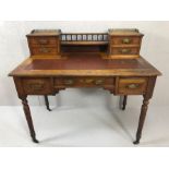Antique writing desk on turned legs and castors with burgundy leather insert and gallery with