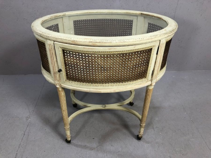 French bijouterie table on fluted tapering legs and castors, of oval form, with glass and wicker
