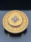 Victorian Gold coloured mourning brooch of circular form and set with seed pearls and picture