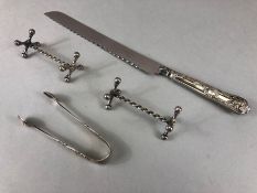 Silver handled Bread knife, a silver hallmarked pair of sugar nips with a pair of knife rests