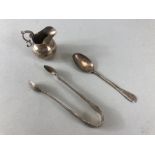 Three silver hallamrked items to include sugar nips a miniature cream jug and a spoon