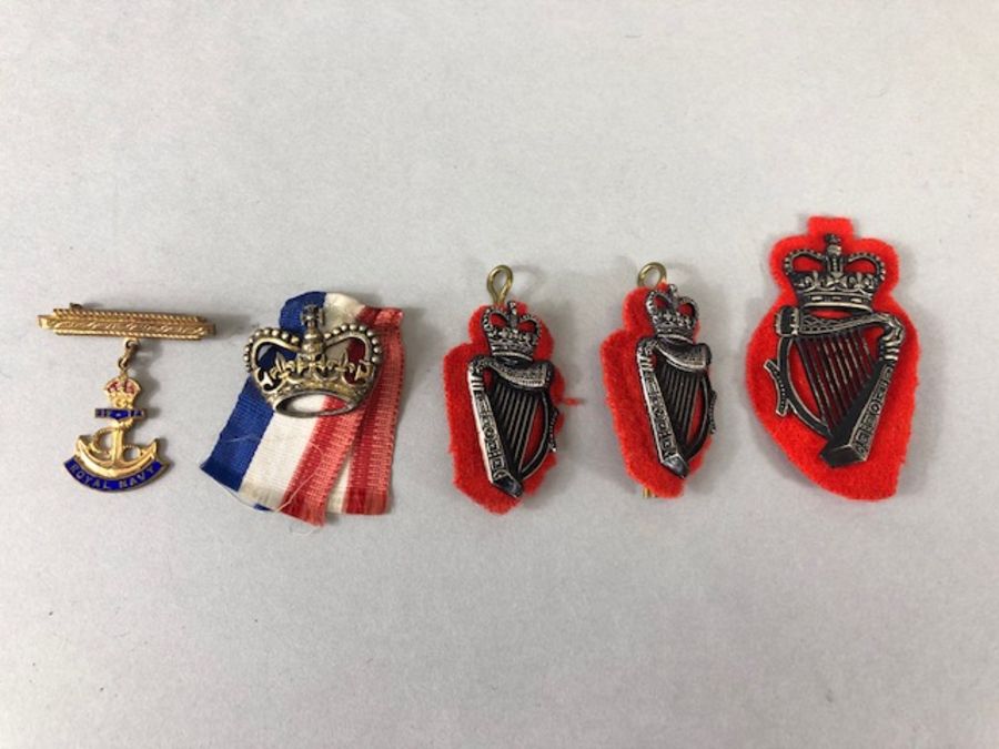 Collection of military cap badges to include gold coloured Royal Navy pin with blue enamel (5)