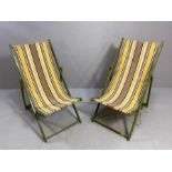 A pair of vintage wooden folding striped fabric deckchairs