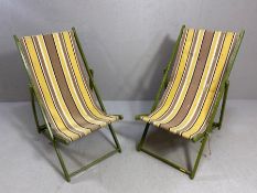 A pair of vintage wooden folding striped fabric deckchairs