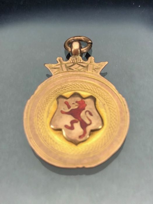 9ct Gold medallion fully hallmarked and decorated with a red rampant Lion and surmounted by a