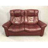 Leather two seater reclining sofa in burgundy, approx 160cm wide