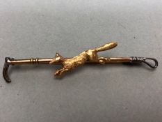 9ct Gold and silver hunting brooch depicting a fox and a riding crop approx 6cm long and 2.8g