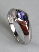 Contemporary 18k white gold ring set with an oval Tanzanite purple/blue stone and flanked by two