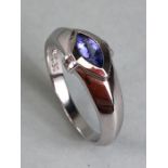 Contemporary 18k white gold ring set with an oval Tanzanite purple/blue stone and flanked by two