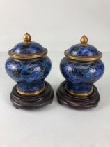 Chinese cloisonne, a pair of cloisonne cobalt blue urn vases with lids on wooden stands
