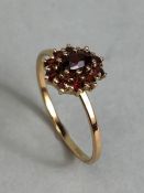 9ct Garnet cluster ring size 'P' with central oval stone surrounded by 10 smaller garnets size