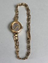 9ct Gold Oval faced watch with silver face and baton numerals on a 9ct gold gate-link bracelet strap