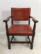 Antique red leather studded elbow chair on turned front legs with cross stretchers