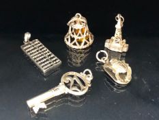 Collection of five charms to include an abacus, bell, key etc