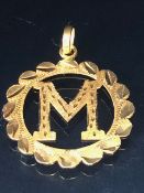 22ct Gold pendant of pierced design for the letter "M" approx 3cm in diameter and 2.2g