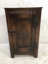 Linen fold bedside cabinet with carved detailing and metal hinges
