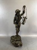 Bronze statue of a seafarer stood on the prow of a boat holding a lantern and knife, approximately