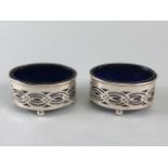Pair of Silver salts with blue glass liners on four ball feet with pierced decoration Hallmarked for