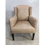 Antique wing back small armchair with red piping and square tapering legs on original castors