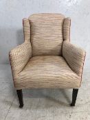 Antique wing back small armchair with red piping and square tapering legs on original castors