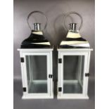 Pair of modern storm lamps, white wooden frames with glass panels and polished metal tops,