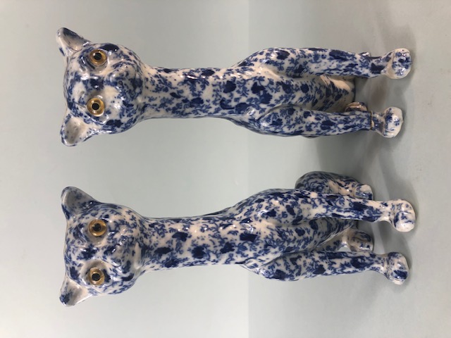 Oriental China, a pair of Chinese long neck cats with cobalt decoration of leaves and tendrils the