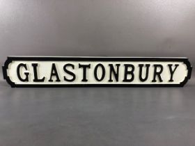 Modern wooden sign, 'GLASTONBURY'', in the form of a cast iron road sign, approx 83cm in length