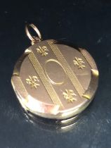 9ct gold round locket with a fleur de lil and lining, design approximately 3.55g