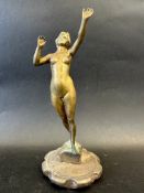 A polished brass car accessory mascot in the form of a standing female nude, radiator cap mounted,
