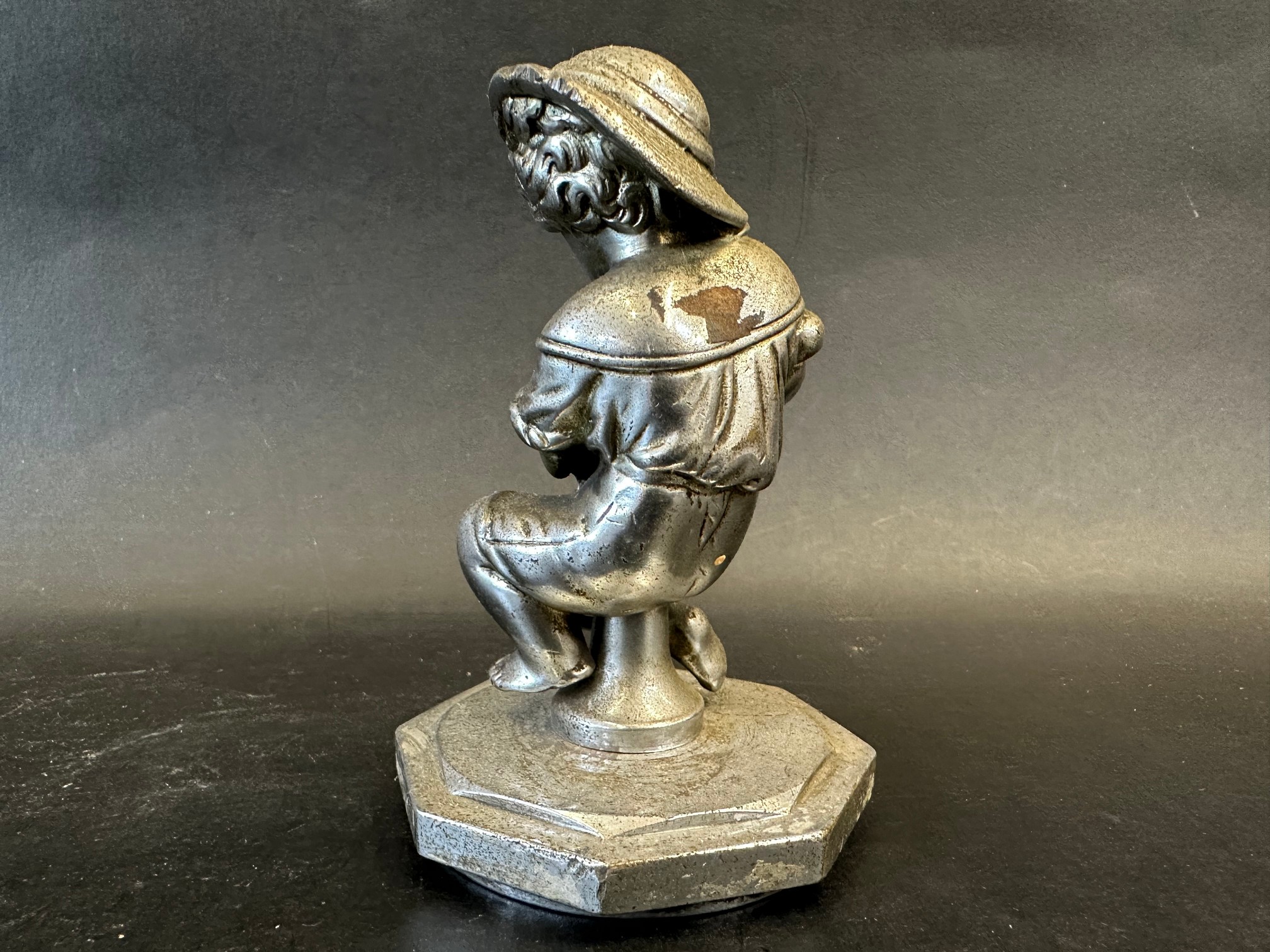 A car mascot in the form of a seated child holding a hammer and chisel, radiator cap mounted, - Image 3 of 3