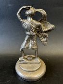 A car accessory mascot in the form of a knight with feathered hat and shield looking out to the