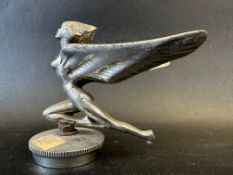 A car accessory mascot in the form of a winged female nude on one knee, radiator cap mounted,