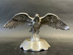 A car accessory mascot in the form of a bird of prey perched on a sphere, display base mounted,