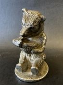 A car mascot in the form of a seated bear holding a pot of honey, no markings to base, possibly