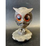 A car mascot depicting an owl perched, with large orange and black glass eyes, possibly French,