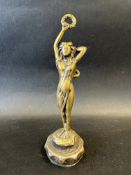 A brass car accessory mascot in the form of a lady holding a laurel wreath aloft, radiator cap