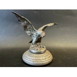 A car accessory mascot in the form of a bird of prey with outstretched wings, display base