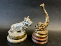 A car mascot in the form of a seated Scottie dog on display base, approx 3 1/2" wide and a fish on