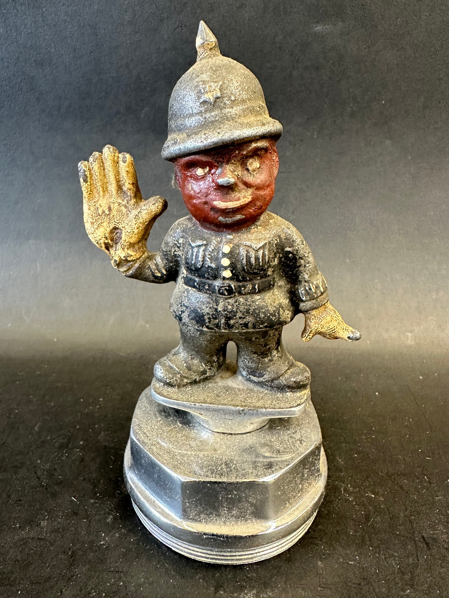 A painted car mascot in the form of a policeman with a disproportionately large, gloved right raised