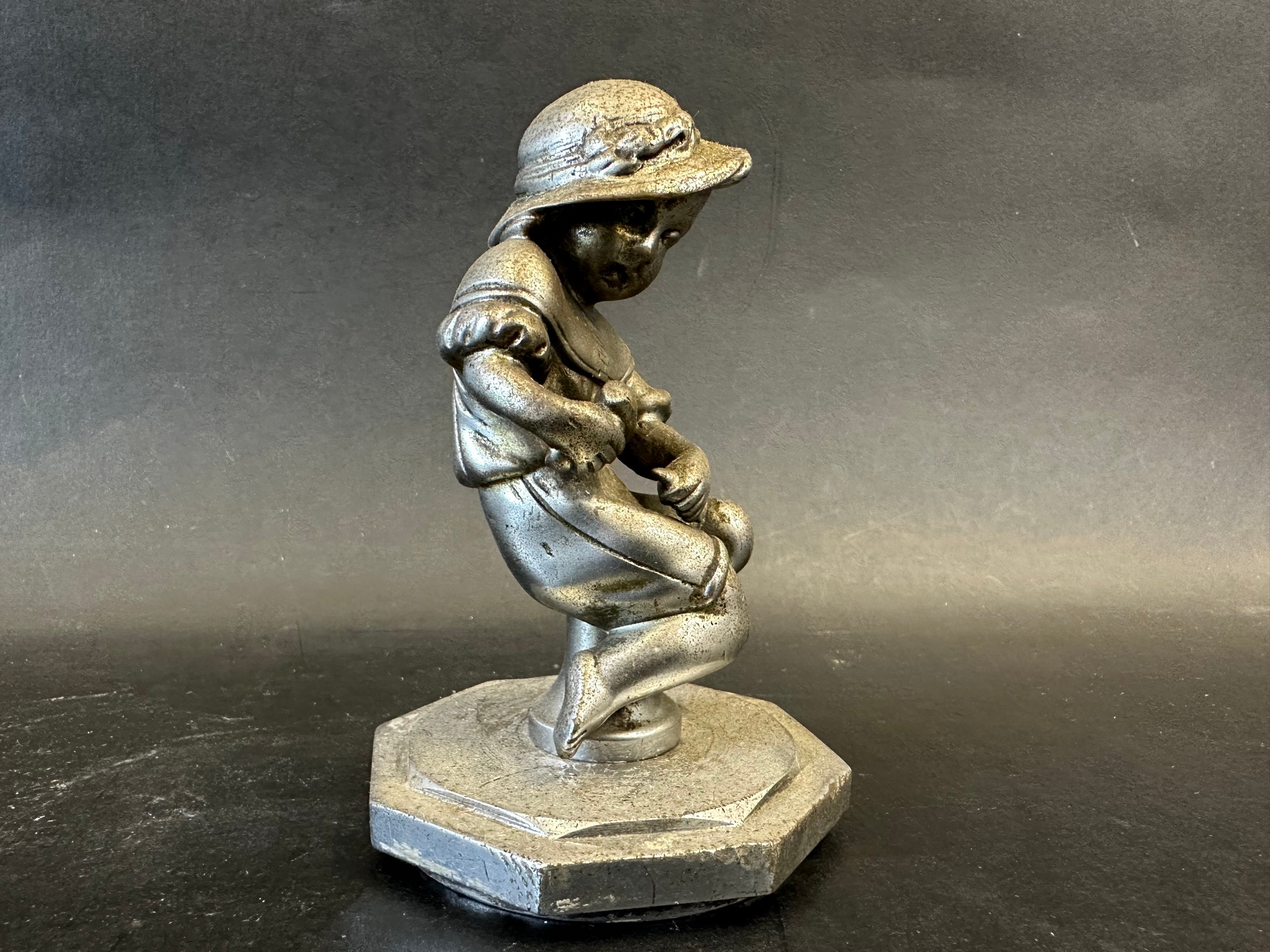 A car mascot in the form of a seated child holding a hammer and chisel, radiator cap mounted, - Image 2 of 3