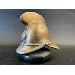 A brass car mascot in the form of a fireman's helmet, metal display base mounted, approx. 4" tall