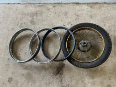 A motorcycle rear wheel and two motorcycle rims.