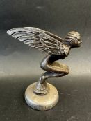 A car accessory mascot in the form of a winged nude crouching female, mounted on a radiator cap,
