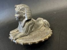 An Armstrong-Siddeley car mascot in the form of a recumbant sphinx on oval, ridge-edged cap, approx.