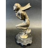 A car mascot in the form of a crouching lady clutching her wind-swept scarf, display base mounted,