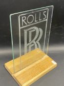 A small glass panel etched with Rolls Royce 'RR', mounted on a contemporary wooden stand, overall