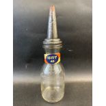 An American glass quart oil bottle with grade band on the neck and tin spout.