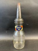 An American glass quart oil bottle with grade band on the neck and tin spout.